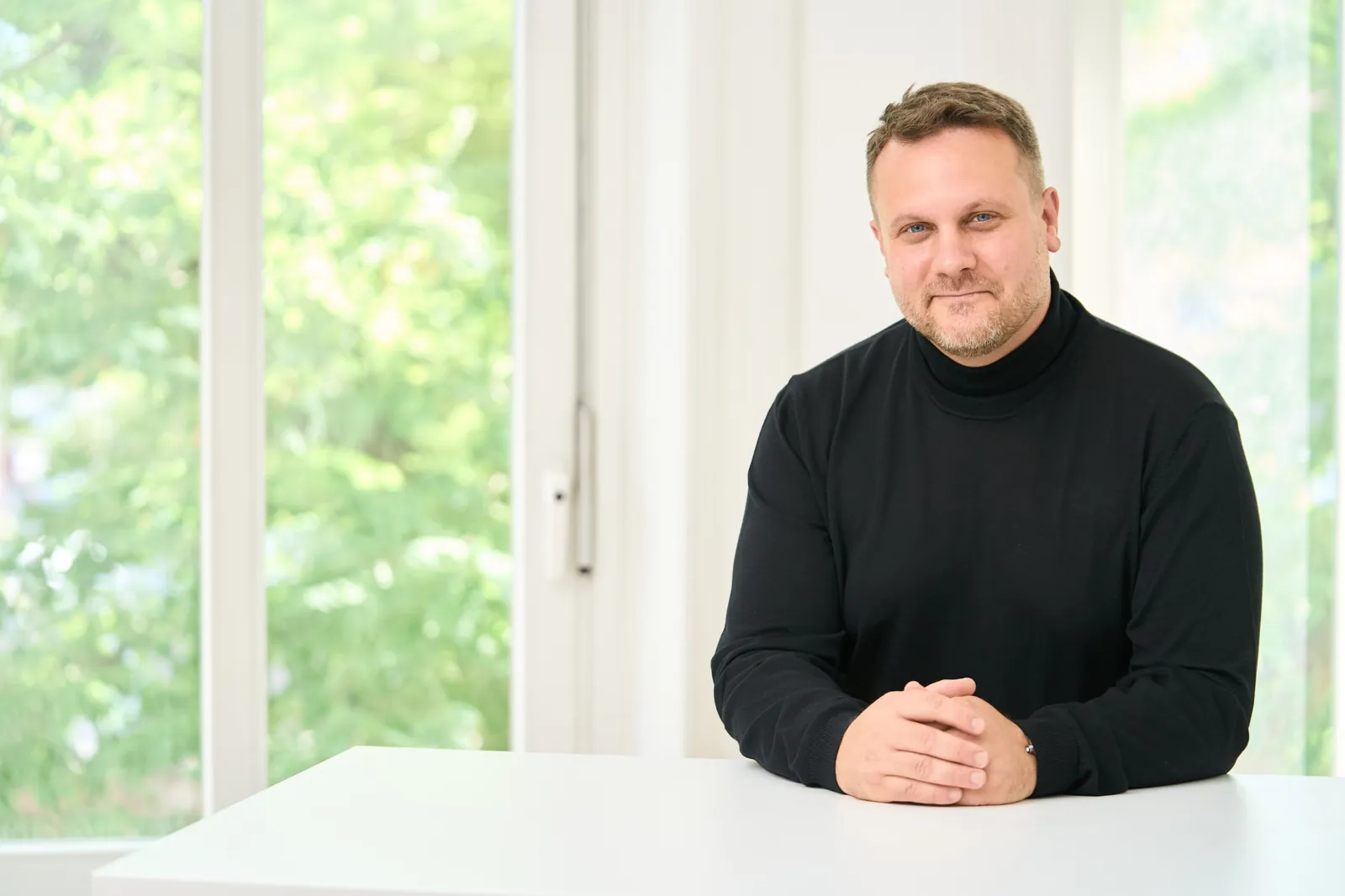 Rechtsanwalt Dr. David Slopek mit gefalteten Händen am Tisch der Kanzlei – Vertriebsverträge und Vertriebssysteme
