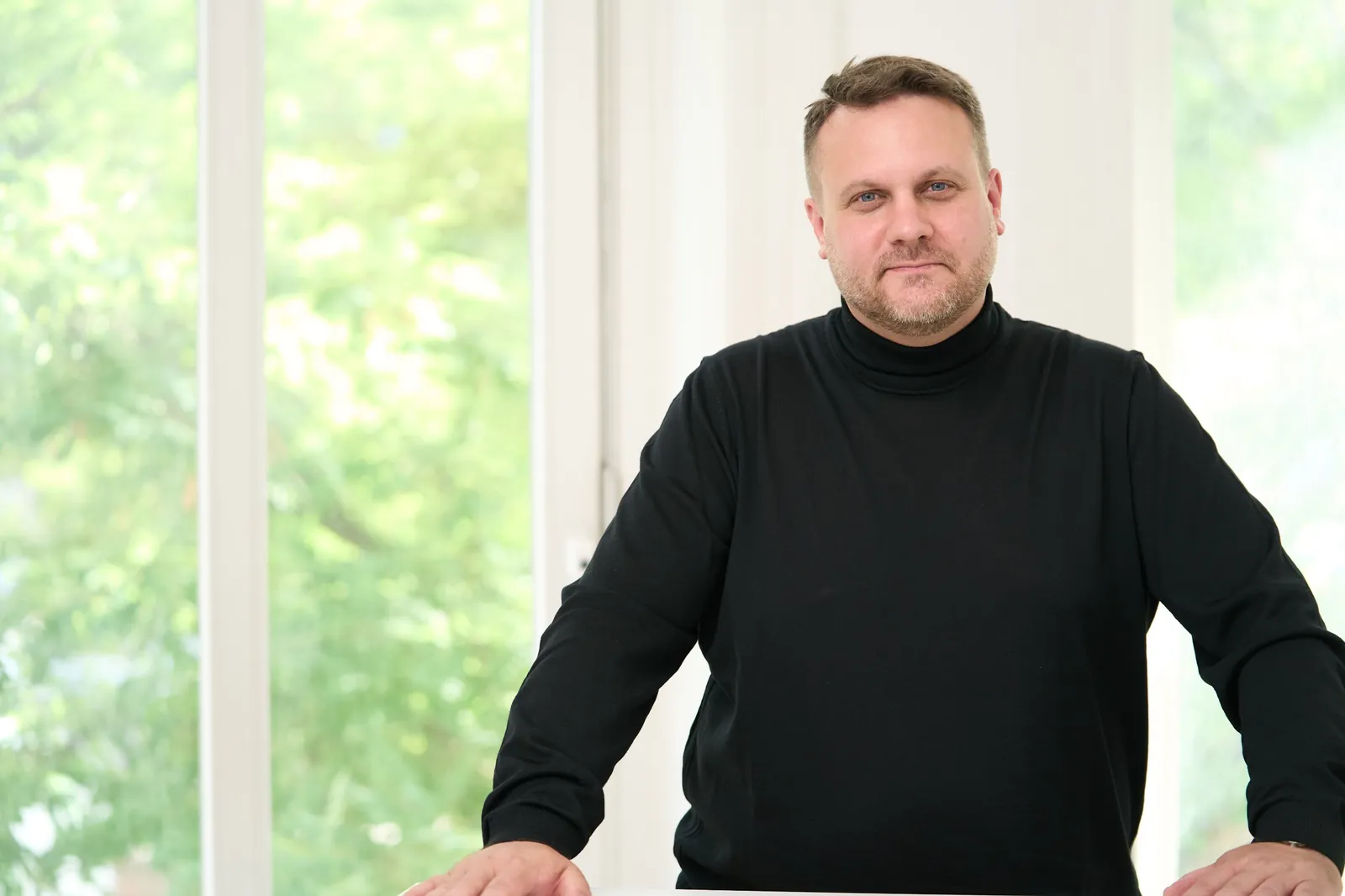 Rechtsanwalt Dr. David Slopek am Tisch vor der Fensterfront der Kanzlei – Missbrauch von Marktmacht bei Slopek Rechtsanwälte